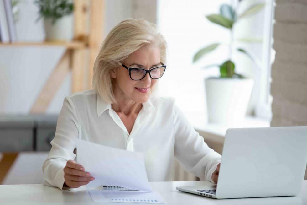 business woman reading letter while on laptop