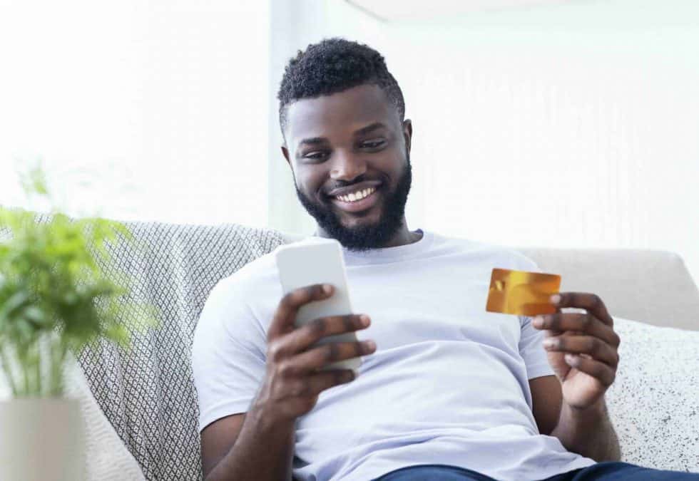 man on sofa activating card on his mobile device